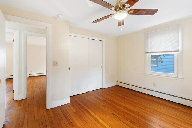 unfurnished bedroom featuring a baseboard heating unit, light wood-style flooring, and a closet
