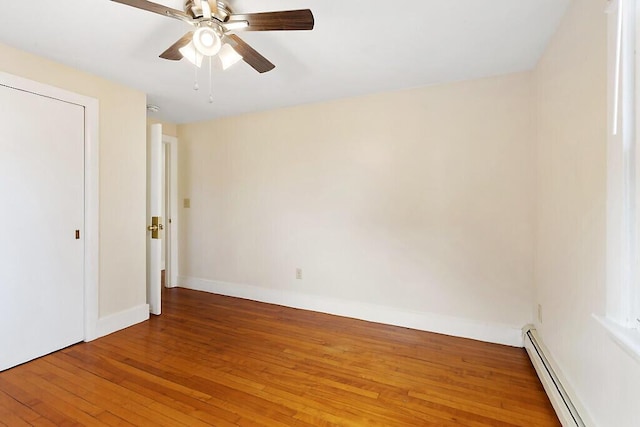 unfurnished bedroom featuring a baseboard heating unit, a ceiling fan, baseboards, and hardwood / wood-style floors