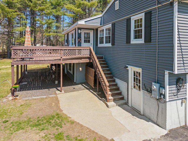 rear view of house featuring driveway, stairs, a carport, and a deck