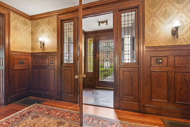 70 Carroll St, Portland, ME 04102 - foyer entrance with wallpapered walls, dark wood finished floors, wainscoting, and ornamental molding