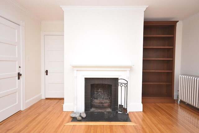 105 N St Unit 3, Portland, ME 04101 - unfurnished living room featuring radiator heating unit, wood finished floors, ornamental molding, a fireplace with flush hearth, and baseboards