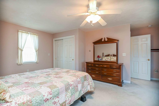 bedroom featuring baseboards, ceiling fan, a closet, and light colored carpet
