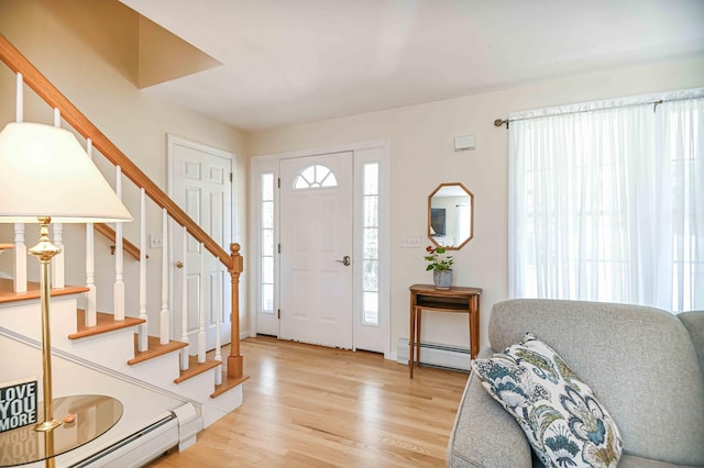 foyer with light wood-style floors, a baseboard radiator, baseboard heating, and stairs