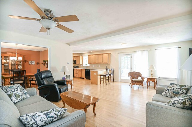 living area with light wood-style floors and ceiling fan with notable chandelier