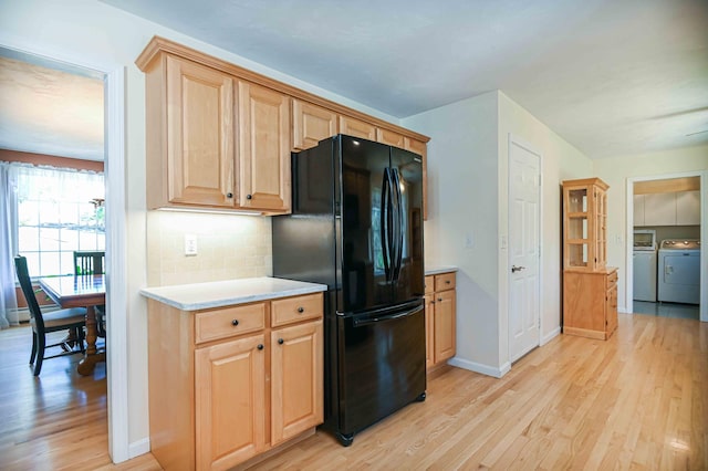 kitchen featuring freestanding refrigerator, light wood-style floors, light countertops, tasteful backsplash, and independent washer and dryer