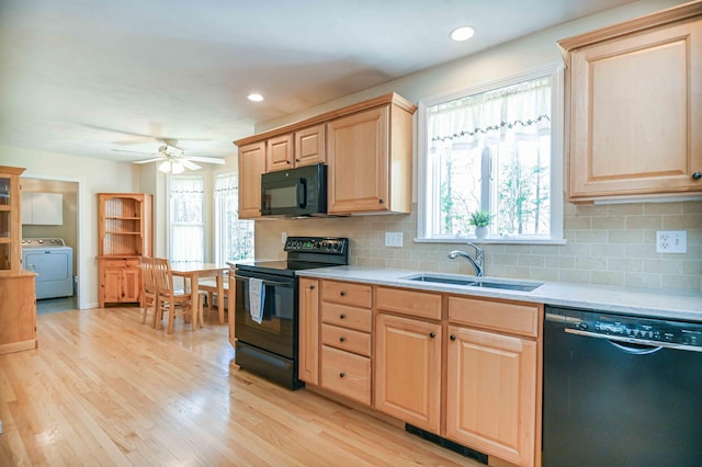 kitchen featuring a sink, light brown cabinets, light countertops, washer / dryer, and black appliances