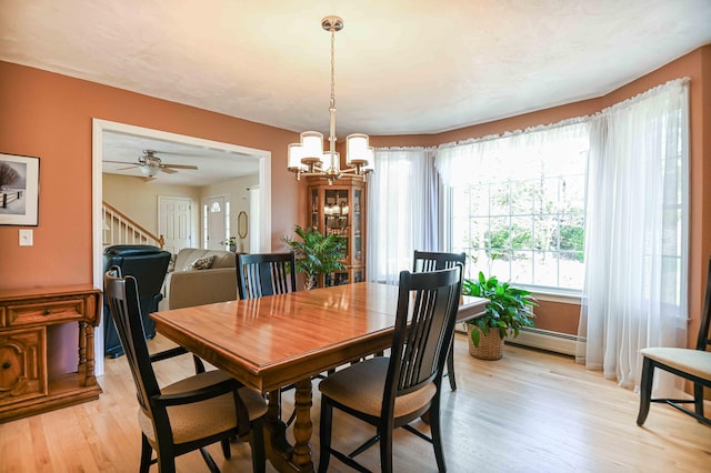 dining room with a baseboard radiator, light wood finished floors, and ceiling fan with notable chandelier
