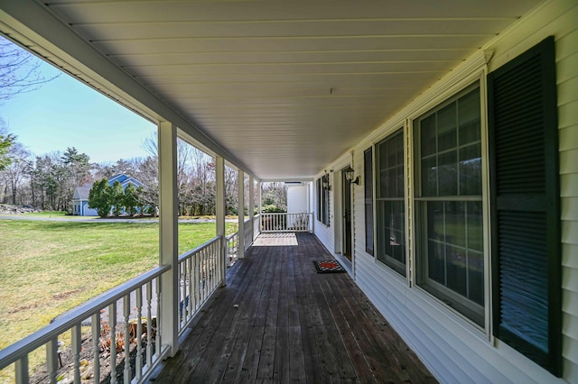 wooden deck featuring a porch and a lawn