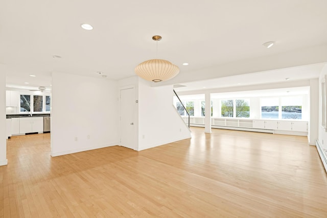 unfurnished living room featuring a ceiling fan, baseboards, a baseboard heating unit, recessed lighting, and light wood-style flooring