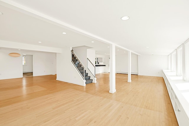 below grade area with recessed lighting, baseboard heating, stairs, and light wood-style flooring