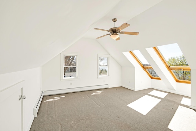 bonus room with carpet floors, baseboard heating, a baseboard heating unit, vaulted ceiling with skylight, and a ceiling fan