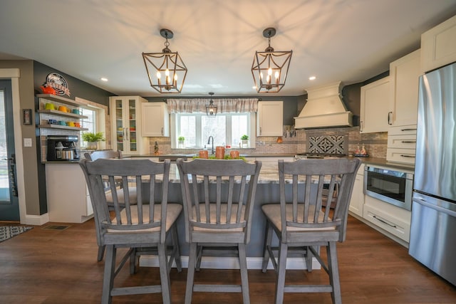 219 Middle Rd, Skowhegan, ME 04976 - kitchen with custom range hood, appliances with stainless steel finishes, a chandelier, white cabinets, and decorative backsplash
