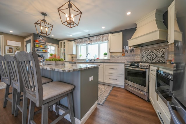 219 Middle Rd, Skowhegan, ME 04976 - kitchen featuring premium range hood, stainless steel range, backsplash, a breakfast bar area, and a chandelier