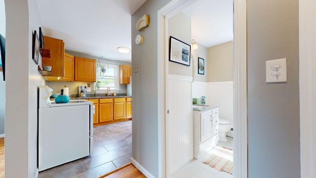 134 Saco St, Westbrook, ME 04092 - kitchen with stove, a sink, and baseboards