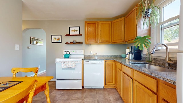 134 Saco St, Westbrook, ME 04092 - kitchen with white appliances, arched walkways, a sink, light tile patterned floors, and dark stone counters