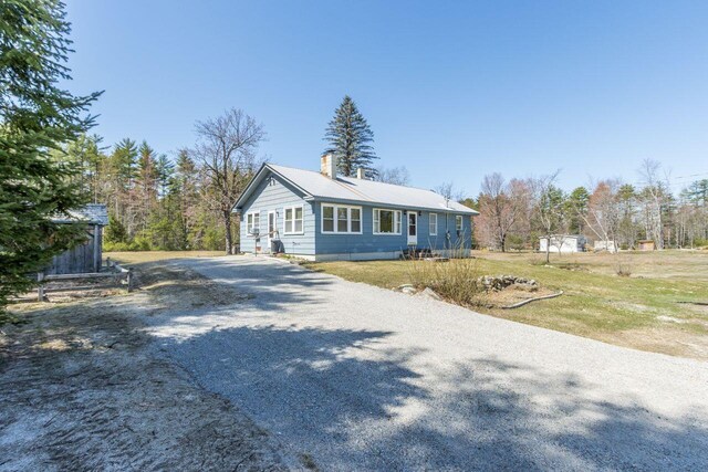 view of front of property with a chimney, driveway, and a front yard