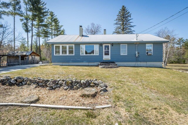 view of front facade with a front lawn, a chimney, an outdoor structure, and metal roof
