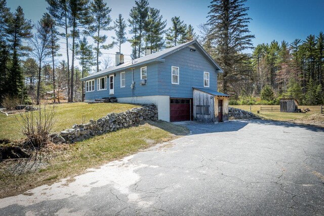 view of front of home featuring driveway, a chimney, a front yard, and a garage
