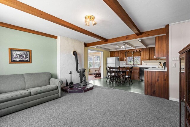 living area with a wood stove and beam ceiling
