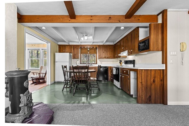 kitchen featuring plenty of natural light, black appliances, beam ceiling, and light countertops