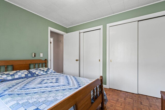 bedroom featuring two closets and crown molding