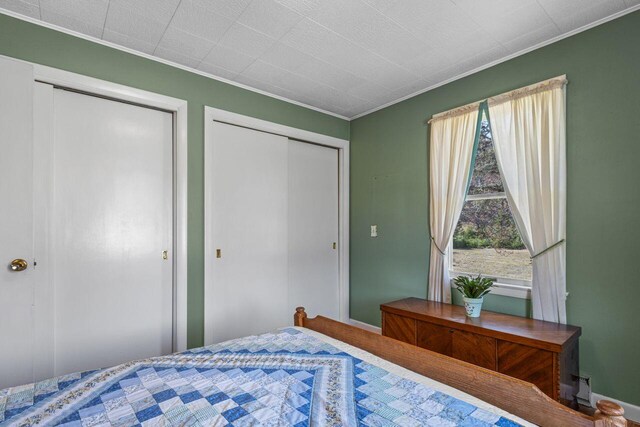 bedroom with multiple closets, crown molding, and baseboards