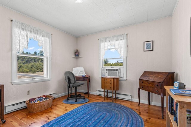 interior space featuring a baseboard heating unit, cooling unit, wood finished floors, and ornamental molding