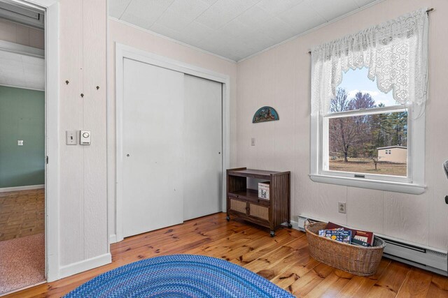 bedroom with crown molding, wood finished floors, and a closet