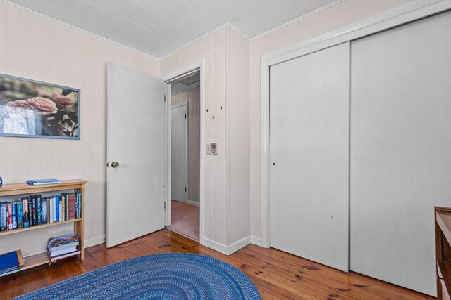 bedroom featuring a closet, hardwood / wood-style flooring, and ornamental molding