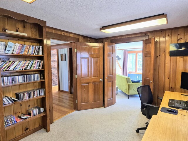 home office with wooden walls, carpet floors, and a textured ceiling