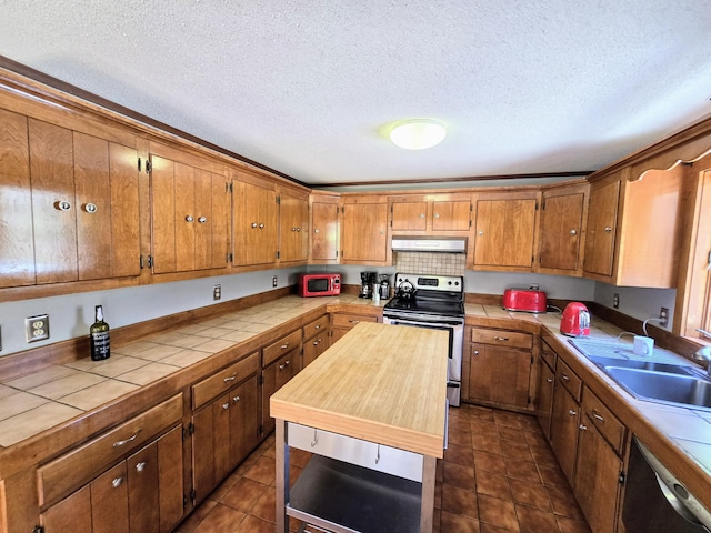 kitchen with appliances with stainless steel finishes, brown cabinets, under cabinet range hood, and tile countertops