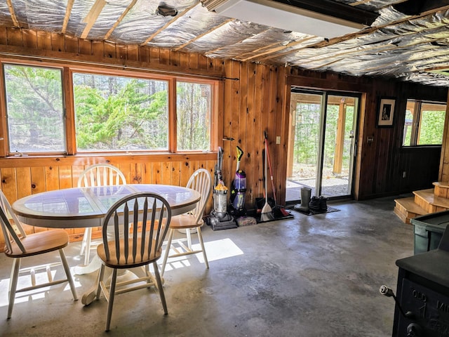 dining space featuring concrete flooring, wooden walls, and a healthy amount of sunlight