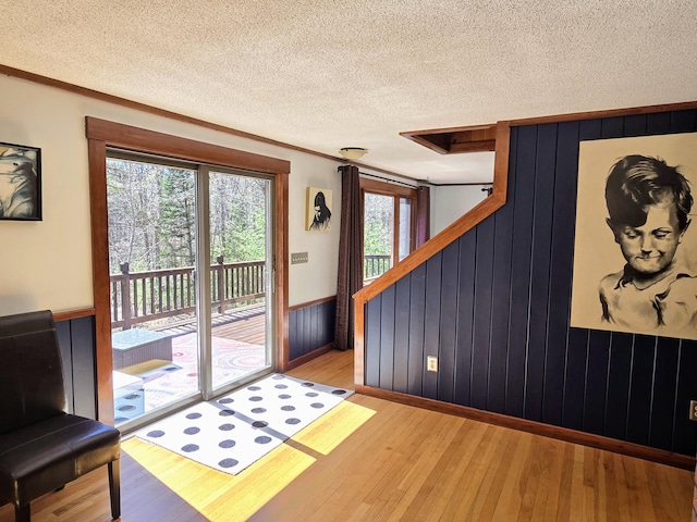 entryway with crown molding, wainscoting, wood-type flooring, a textured ceiling, and wood walls