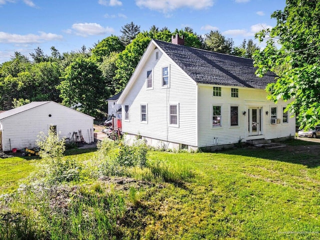 rear view of house featuring a lawn, a shingled roof, a chimney, and entry steps