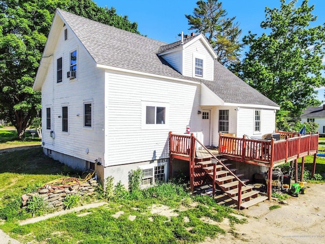 rear view of property with stairway, roof with shingles, and a deck