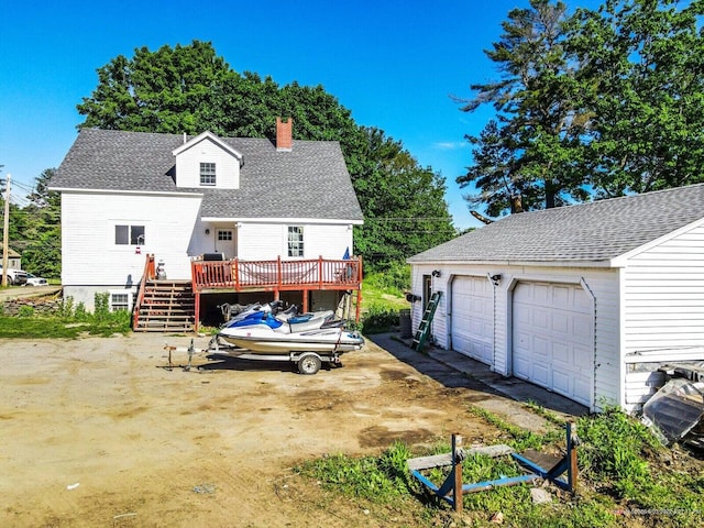 exterior space featuring a chimney, a wooden deck, a garage, a shingled roof, and stairway