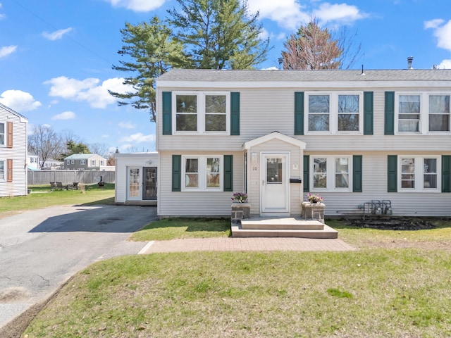 colonial-style house featuring fence, driveway, and a front yard