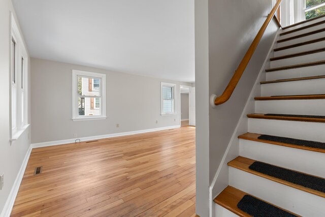 staircase with visible vents, baseboards, and hardwood / wood-style flooring