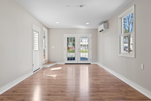 interior space featuring baseboards, french doors, a wall unit AC, and wood finished floors