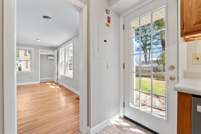 doorway featuring plenty of natural light, a wall unit AC, and light wood-type flooring