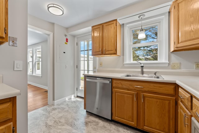 kitchen featuring decorative light fixtures, stainless steel dishwasher, a sink, light countertops, and baseboards