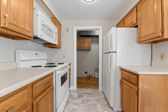 kitchen with brown cabinetry, light countertops, baseboards, and white appliances