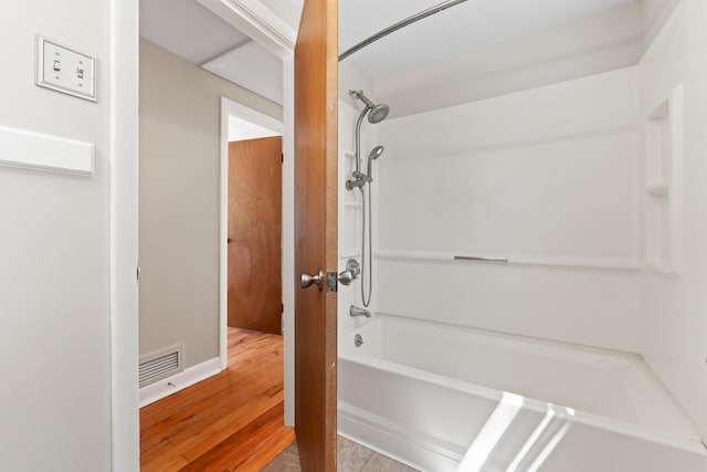 full bath featuring baseboards, visible vents, bathing tub / shower combination, and wood finished floors