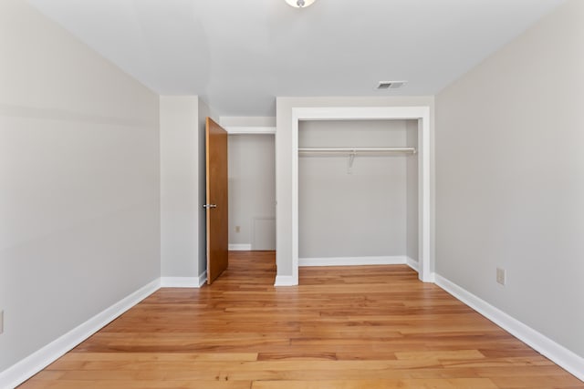 unfurnished bedroom featuring visible vents, light wood-style floors, baseboards, and a closet