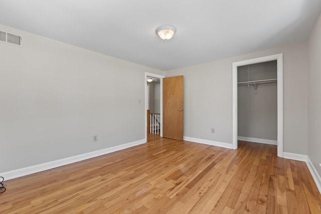 unfurnished bedroom with baseboards, visible vents, light wood finished floors, and a closet