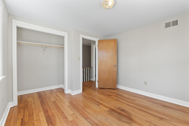 unfurnished bedroom with light wood-style floors, baseboards, a closet, and visible vents