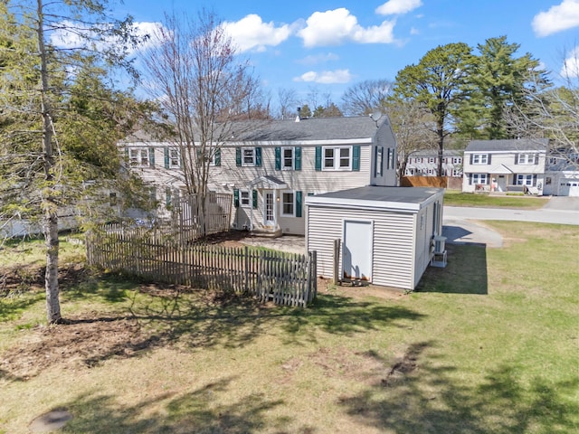 back of house featuring a storage unit, an outdoor structure, fence, and a yard