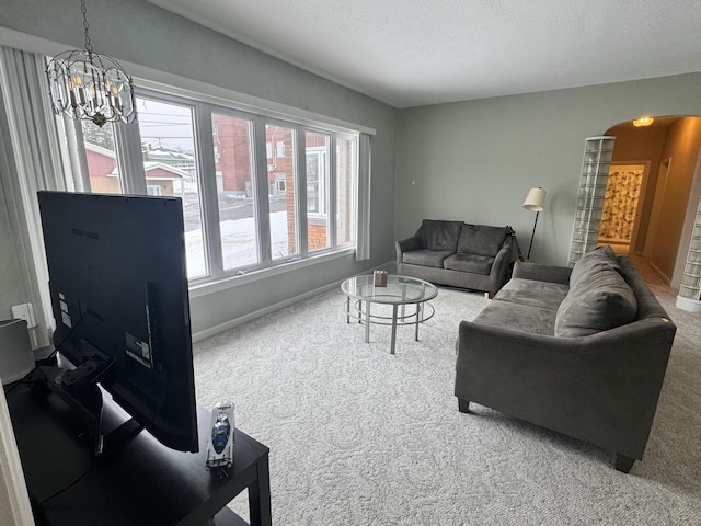 living room with a textured ceiling, arched walkways, carpet floors, baseboards, and a notable chandelier