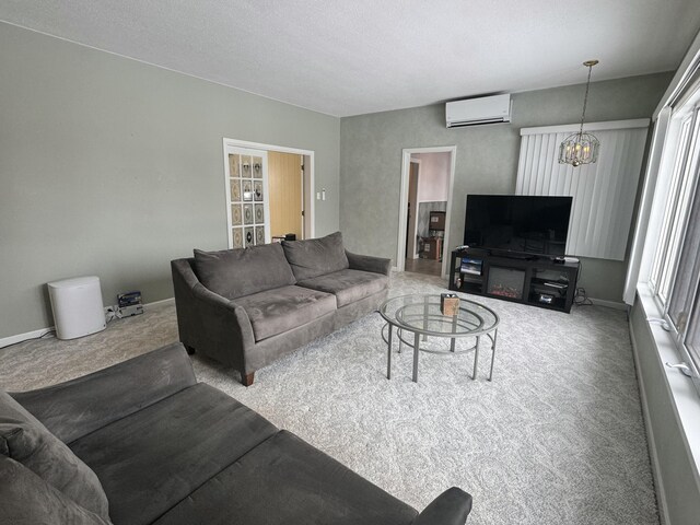 living room featuring baseboards, a wall unit AC, a chandelier, and carpet