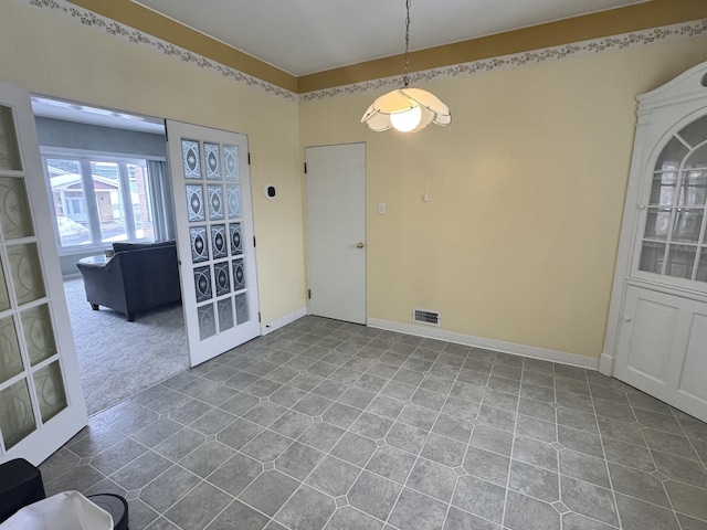 unfurnished dining area featuring dark tile patterned floors, visible vents, baseboards, and french doors
